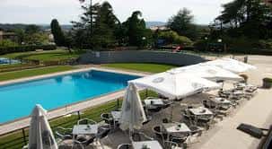 Vista panorámica de la piscina y zona de descanso con sombrillas y mesas al aire libre