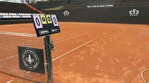 Cancha de tenis de tierra batida con marcador y red en primer plano