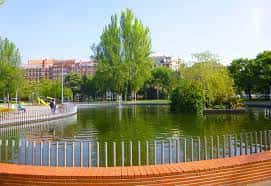 Vista diurna del lago central del Parque del Norte con árboles y edificios al fondo
