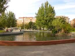 Paseo junto al lago en el Parque del Norte con personas caminando y vegetación circundante