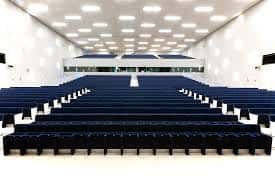 Interior del auditorio principal con butacas azules dispuestas en gradas y techo con iluminación integrada