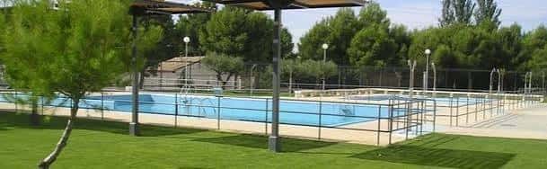 Vista panorámica de la piscina del CDM San Gregorio con césped y pérgola