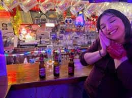 Cliente sonriendo en la barra del bar Road by Alice con iluminación colorida