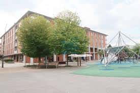 Vista exterior de la plaza Sagastieder con zona de juegos infantiles y árboles