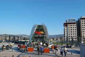Plaza pública con estructura de vidrio y personas caminando en A Salgueira