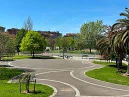 Plaza central del parque con senderos curvos, bancos y palmeras en un día soleado
