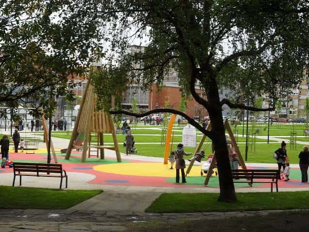 Zona de juegos infantiles con estructuras de madera y suelo de colores en el Parque Severo Ochoa