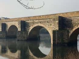 Vista frontal del Puente Romano de Saamasas reflejado en el río Miño