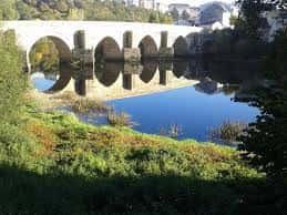Puente romano de Saamasas en un día soleado con reflejo perfecto en el agua