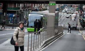 Vista de la estación de tranvía de Basurto con el vehículo verde y pasajeros