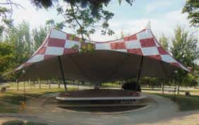 Escenario al aire libre con techo a cuadros rojos y blancos en el Parque de la Paz