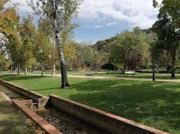Paisaje del parque con árboles, césped y canal de agua en primer plano