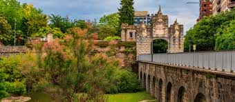 Vista panorámica del parque con murallas históricas y puente de arcos