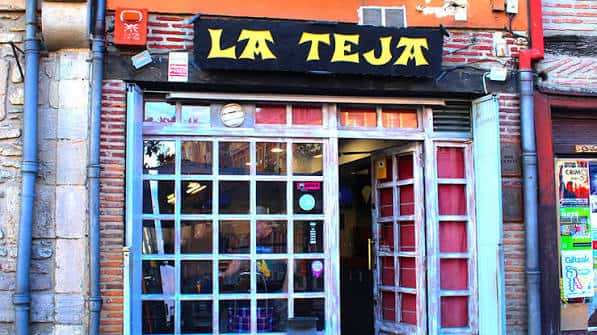 Fachada del Bar La Teja en Vitoria con letrero amarillo y puertas de cristal