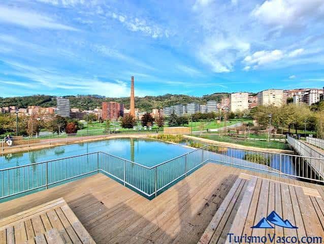 Vista panorámica del Parque Etxebarria con estanque y chimenea industrial al fondo