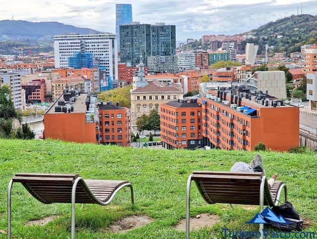 Mirador natural con bancos y vista urbana de Bilbao desde la colina