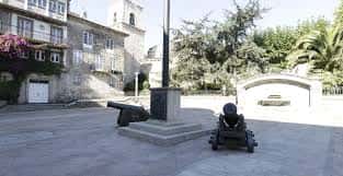 Detalle de los cañones históricos en la plaza con fondo de edificios antiguos y árboles