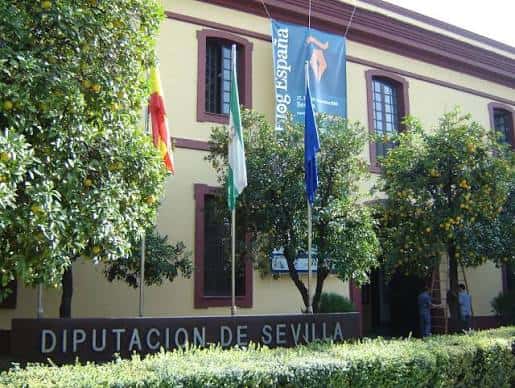 Fachada principal de la Diputación de Sevilla con banderas y árboles de naranjos