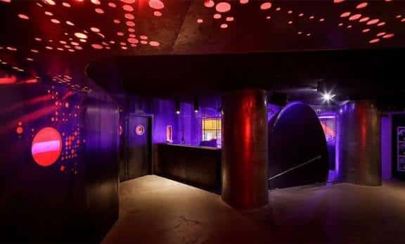 Interior del club con techo de luces rojas y columnas metálicas