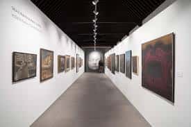 Galería de exposiciones con obras de arte realista en las paredes