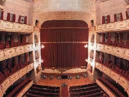 Vista general del interior del teatro con cortina roja y escenario iluminado