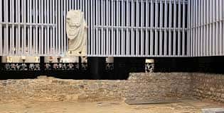 Interior del Museo Foro Romano Molinete con fachada de listones verticales y escultura romana