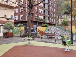 Detalle de la zona de juegos con columpios y bancos en el parque de La Peña