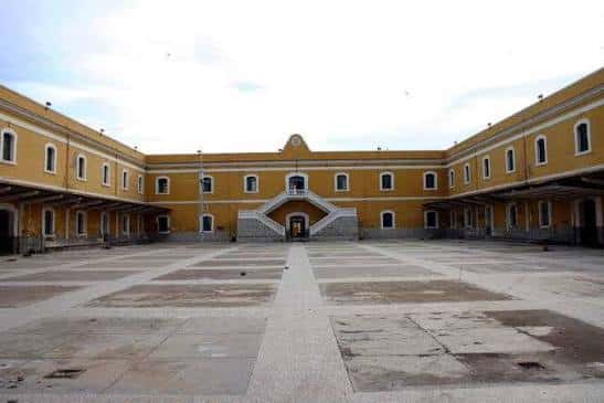 Patio central del cuartel con fachada amarilla y escalinata principal, ideal para eventos al aire libre