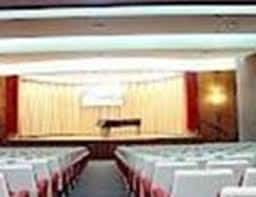 Interior del salón de actos con cortinas doradas y piano en el escenario