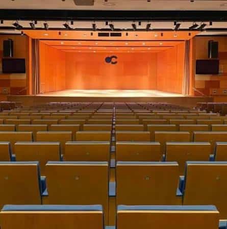 Vista general del auditorio Elcírculo con butacas de madera y escenario iluminado