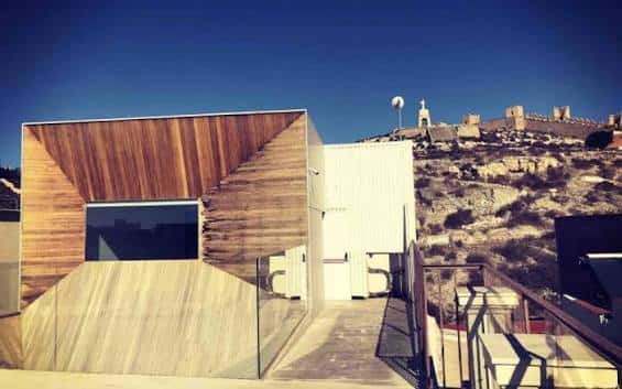 Vista exterior del Centro de Interpretación Patrimonial con fachada de madera y la Alcazaba de Almería al fondo