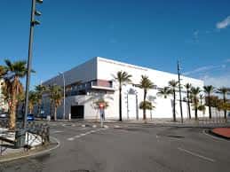Vista exterior del Pabellón Moisés Ruiz con palmeras y cielo despejado