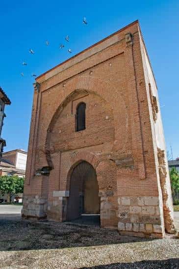 Torre de ladrillo con arco de entrada y cielo despejado