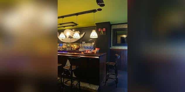 Vista del mostrador del bar con lámparas colgantes y ambiente acogedor