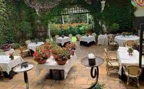 Terraza exterior decorada con plantas y mesas cubiertas para eventos
