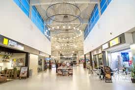 Interior del centro comercial con pasillos amplios, tiendas y decoración luminosa en el techo