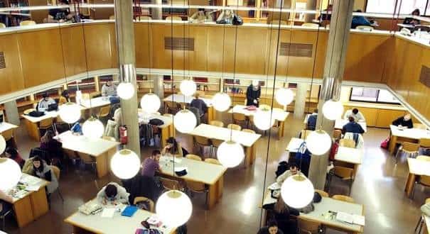 Vista panorámica del interior de la biblioteca desde una altura, mostrando múltiples niveles y lámparas colgantes
