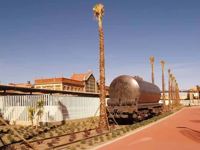 Vista panorámica del parque con vagón de tren histórico y palmeras