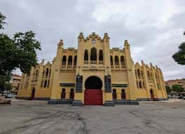 Vista frontal de la Plaza de Toros de Albacete con fachada amarilla y cielo nublado