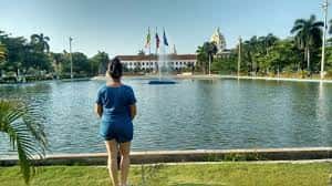 Persona contemplando el lago y el edificio histórico con banderas en el Parque de la Marina
