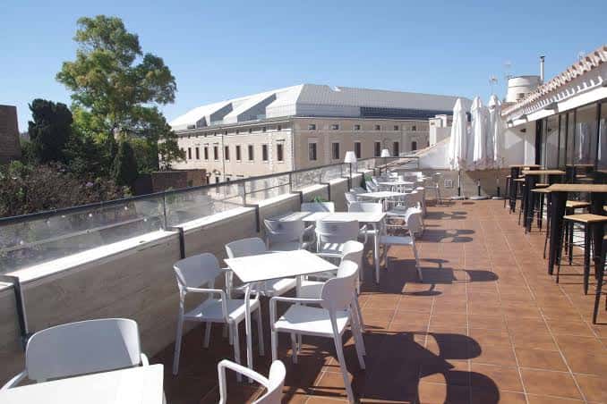 Terraza con mesas blancas y vistas al edificio histórico cercano