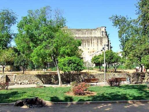 Jardines de Orive con la muralla árabe al fondo y bancos de piedra entre árboles