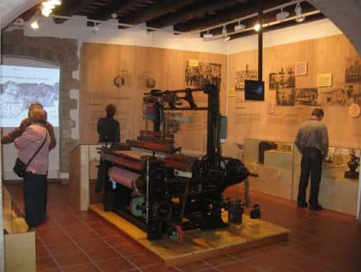Interior del Museo de L'Hospitalet mostrando una prensa histórica y visitantes