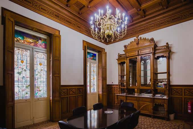 Sala interior del palacete con mobiliario clásico, vitrales y lámpara de araña