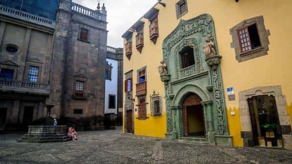 Vista exterior de la fachada principal de la Casa de Colón con su característico arco de piedra y balcones de madera