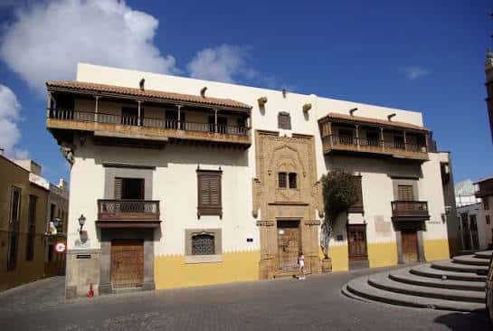 Fachada lateral del edificio con balcones de madera y detalles arquitectónicos coloniales