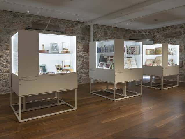 Interior del espacio expositivo con vitrinas iluminadas sobre suelo de madera
