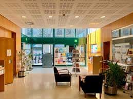 Vista del hall de entrada con mobiliario moderno, plantas y acceso a la calle