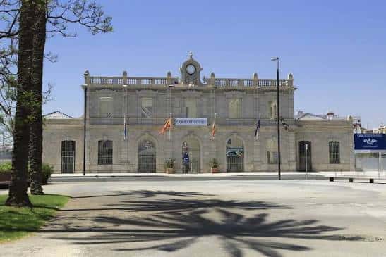 Vista frontal de la fachada histórica de Casa Mediterráneo con banderas y reloj