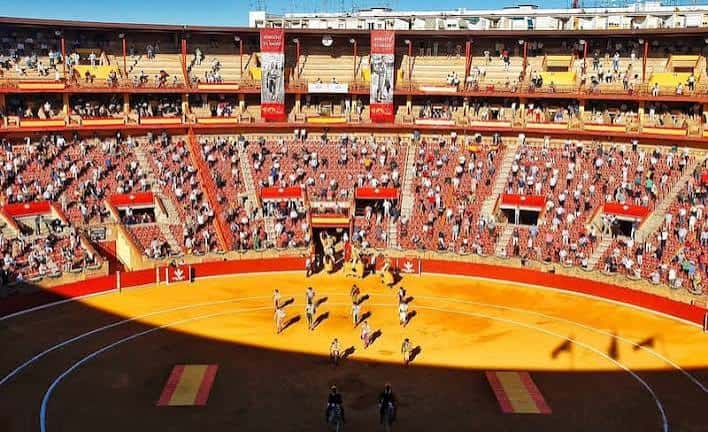 Interior de la plaza con artistas ecuestres en el ruedo y espectadores en las gradas